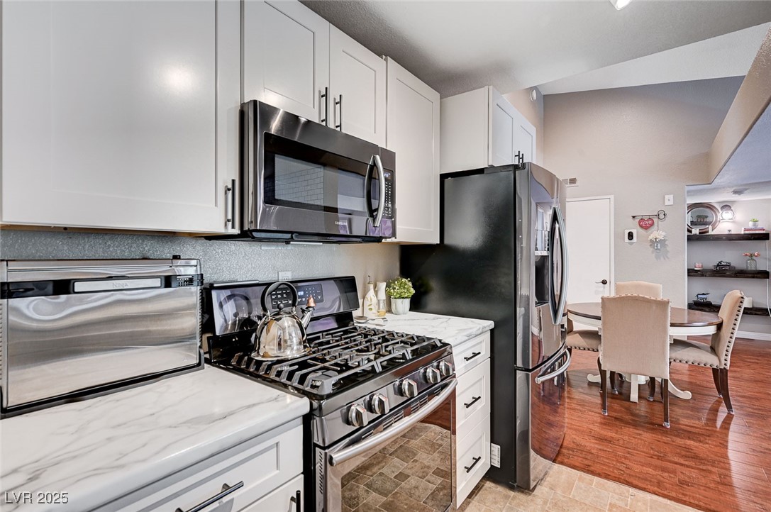 7885 West Flamingo Road, Unit 2023 Las Vegas, NV 89147 - Photo 7 of 34 Kitchen featuring stainless steel appliances, a toaster, white cabinetry, and light stone countertops