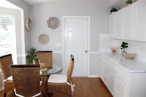 a kitchen with stainless steel appliances kitchen island granite countertop a refrigerator a sink dishwasher and white cabinets with wooden floor