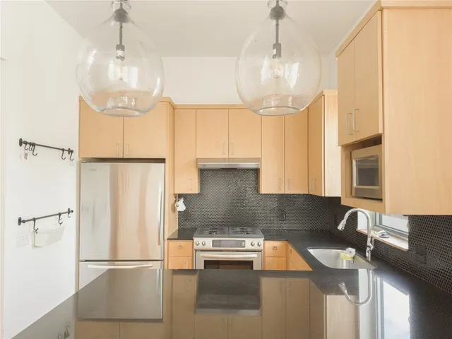 a kitchen with stainless steel appliances granite countertop a refrigerator a sink a stove a washer dryer and a refrigerator