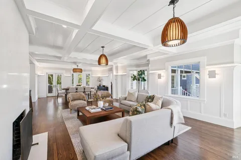 a living room with couches a dining table and chairs with wooden floor