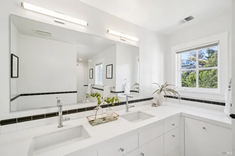 a view of a hallway with wooden floor and a bathroom