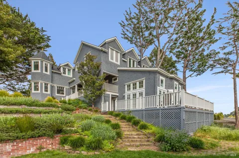 a front view of a house with a yard and potted plants
