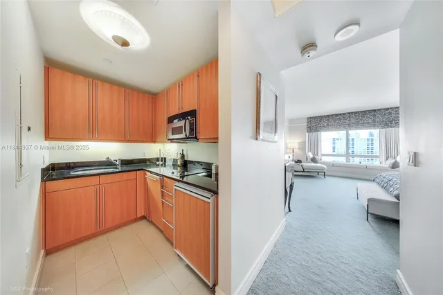 a kitchen with stainless steel appliances granite countertop a refrigerator a sink dishwasher a stove and white cabinets with wooden floor