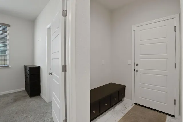 a view of a hallway with wooden floor and a bathroom