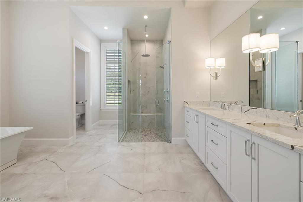 16776 Enclave Circle Naples, FL 34110 - Photo 22 of 50 a bathroom with a granite countertop sink a toilet a mirror and shower