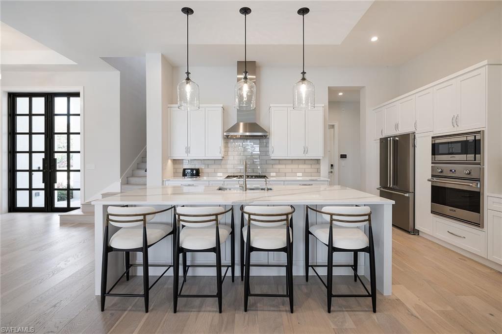 16776 Enclave Circle Naples, FL 34110 - Photo 7 of 50 a kitchen with stainless steel appliances kitchen island a chandelier and refrigerator