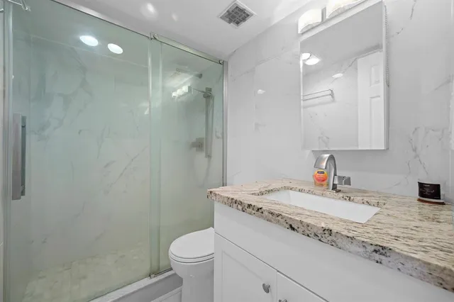 a bathroom with a granite countertop sink a toilet and a mirror