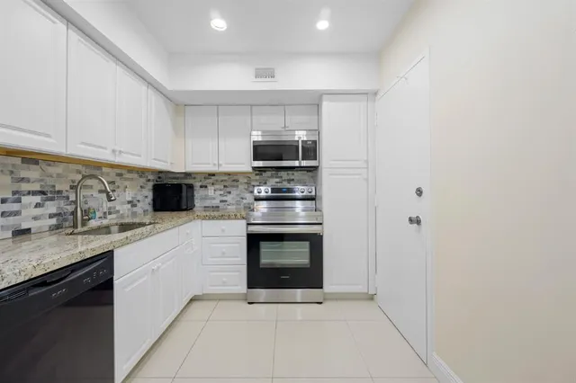 a kitchen with granite countertop a stove sink and cabinets