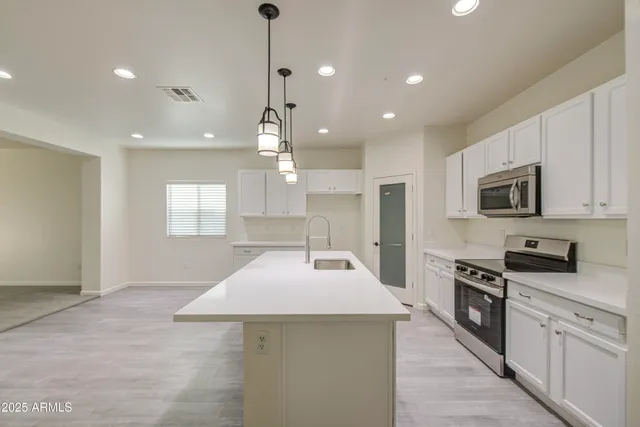 a kitchen with stainless steel appliances kitchen island granite countertop a sink a stove and cabinets