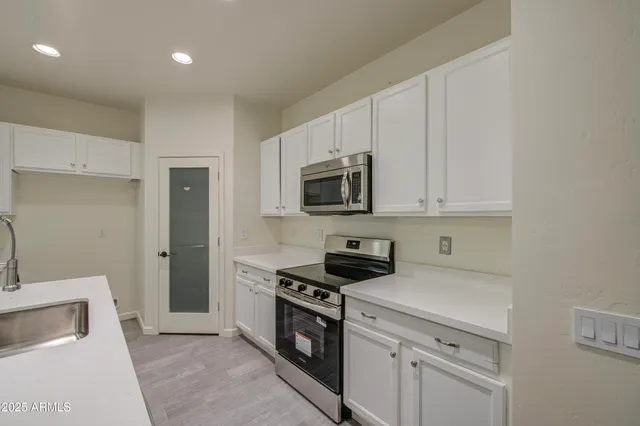 a kitchen with white cabinets and stainless steel appliances