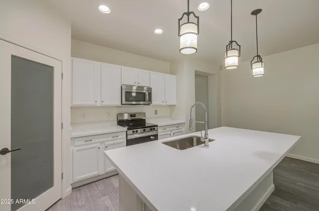 a kitchen with stainless steel appliances a stove a sink a center island a refrigerator and cabinets