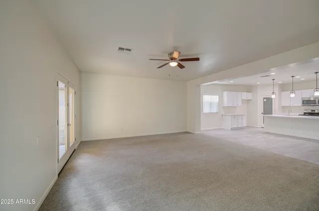 a view of an empty room with a chandelier fan