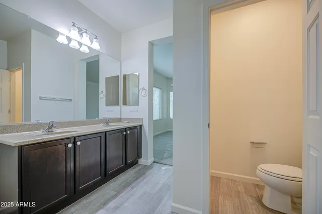 a spacious bathroom with a granite countertop sink a toilet and a mirror