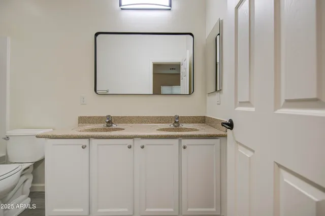 a bathroom with a granite countertop sink a toilet and a mirror