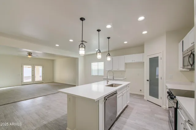 a large white kitchen with a sink a refrigerator and large window