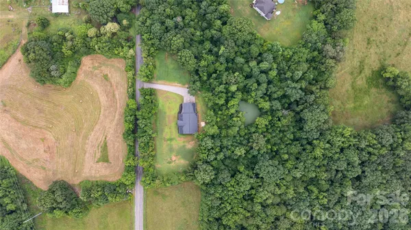 an aerial view of a house with a yard and large trees