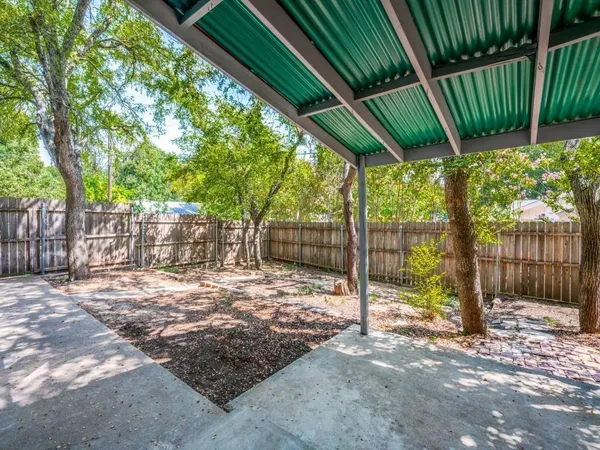 a backyard of a house with table and chairs a barbeque with wooden fence