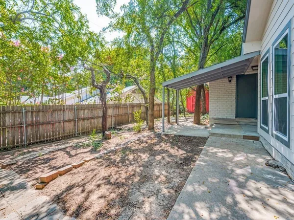 a view of a yard with a large tree and wooden fence