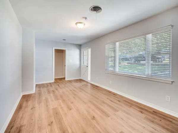 a view of an empty room with wooden floor and a window