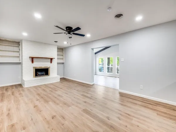 an empty room with wooden floor ceiling fan and windows