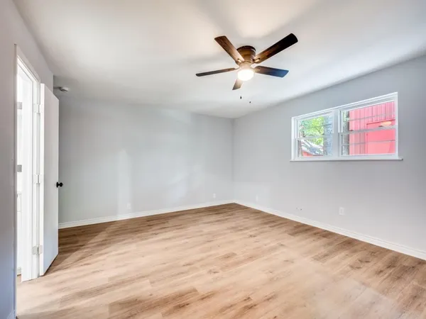 a view of a big room with wooden floor closet and windows in it