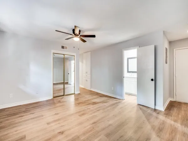 a view of empty room with wooden floor and fan