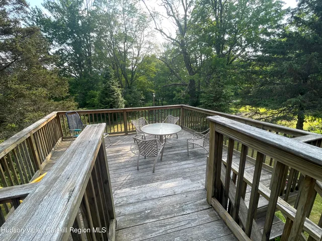 a balcony with wooden floor and yard in the back