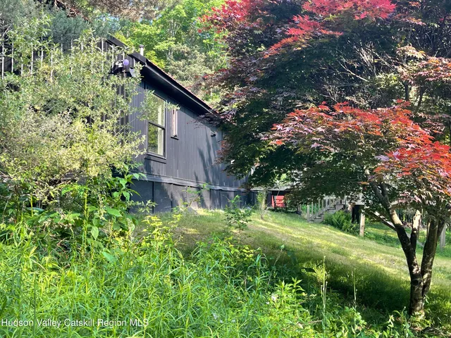a backyard of a house with table and chairs and a large tree