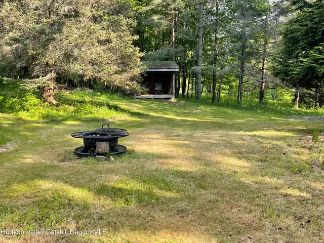 a view of swimming pool with lawn chairs and large trees