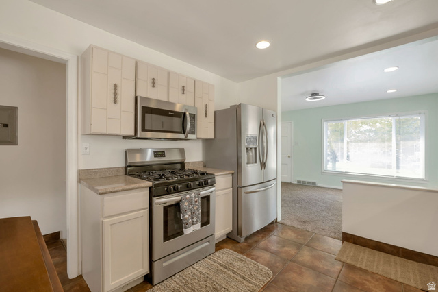 7391 Elm Street Midvale, UT 84047 - Photo 9 of 38 Stainless steel appliances, recessed lighting, tile flooring, light-colored cabinetry, and a large window