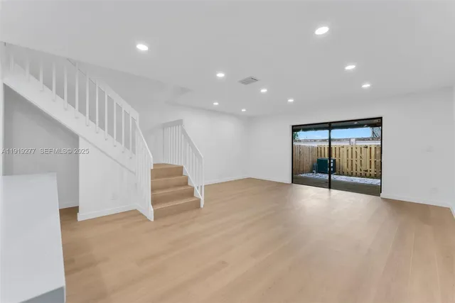 a view of an empty room with wooden floor and windows