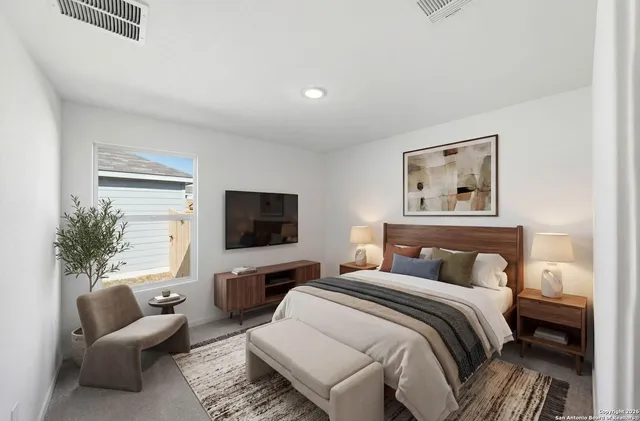 a bedroom with a bed a couch and a flat screen tv