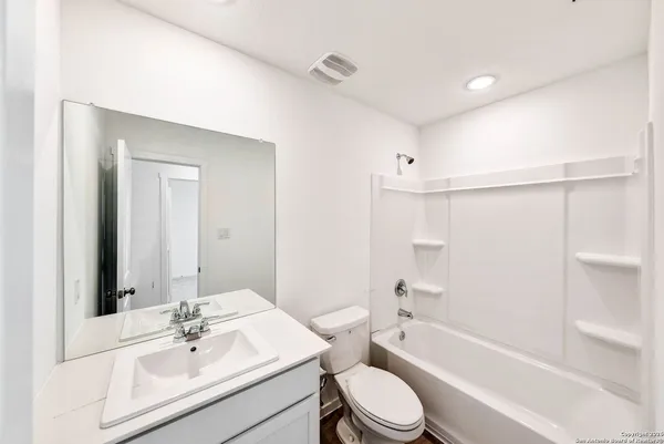 a bathroom with a bathtub shower sink vanity mirror and toilet
