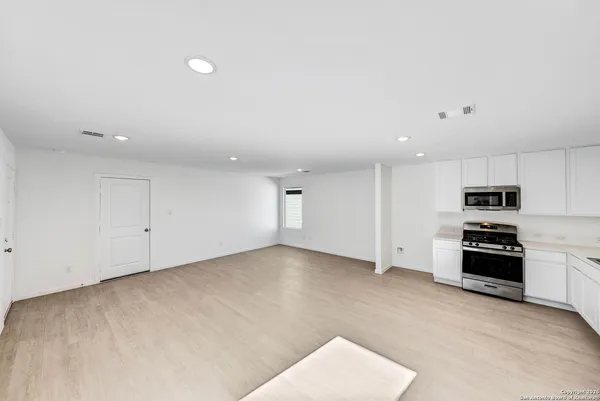 a view of kitchen with stainless steel appliances wooden floor and window