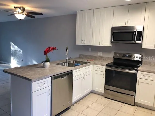 a kitchen with stainless steel appliances granite countertop a sink dishwasher a stove a microwave and cabinets