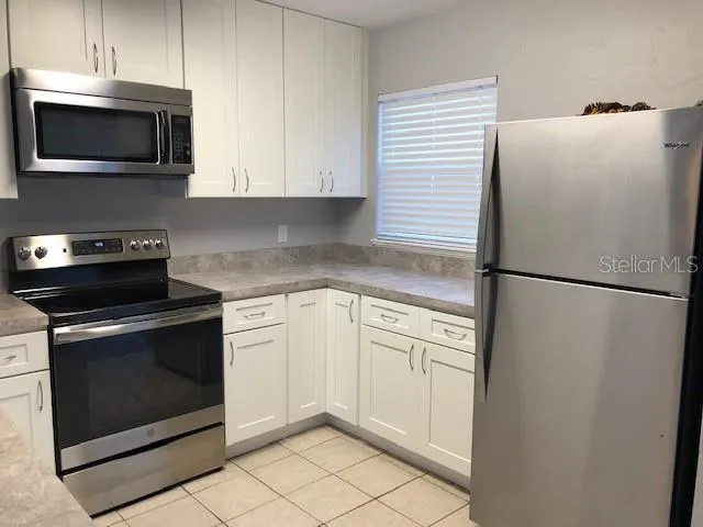 a kitchen with stainless steel appliances white cabinets white stove a microwave and a refrigerator