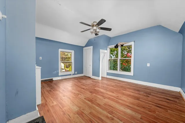 a view of an empty room with window and wooden floor