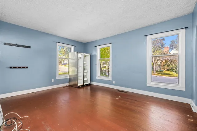 a view of an empty room with window and wooden floor