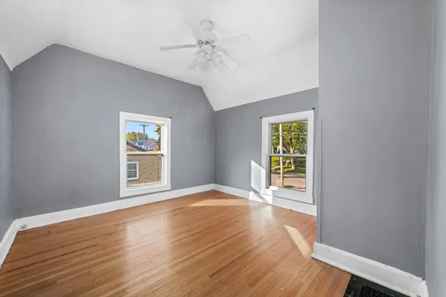 a view of an empty room with a window and wooden floor