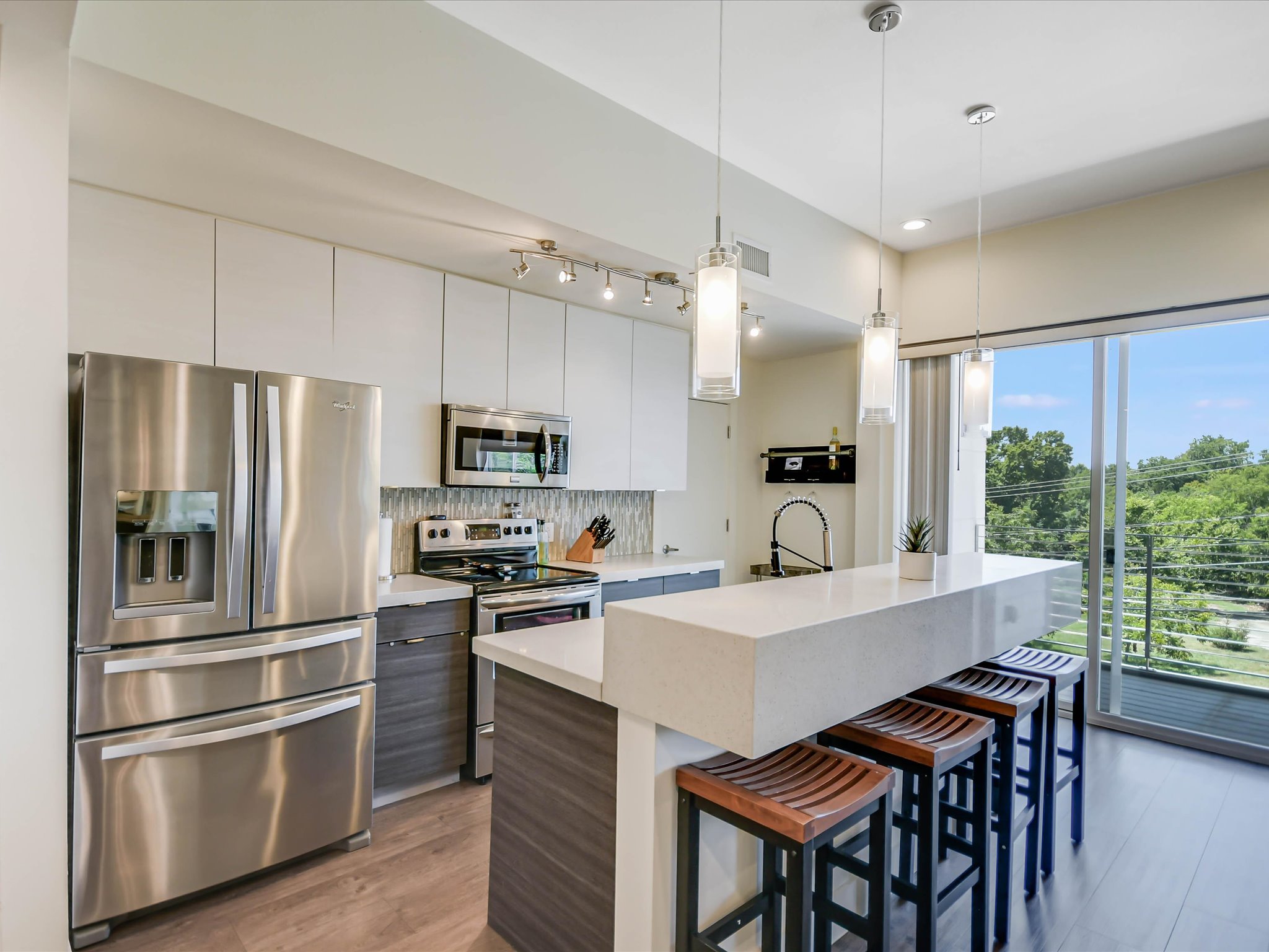 604 North Bluff Drive, Unit 101 Austin, TX 78745 - Photo 12 of 22 Kitchen featuring appliances with stainless steel finishes, modern cabinets, a breakfast bar, tasteful backsplash, and recessed lighting