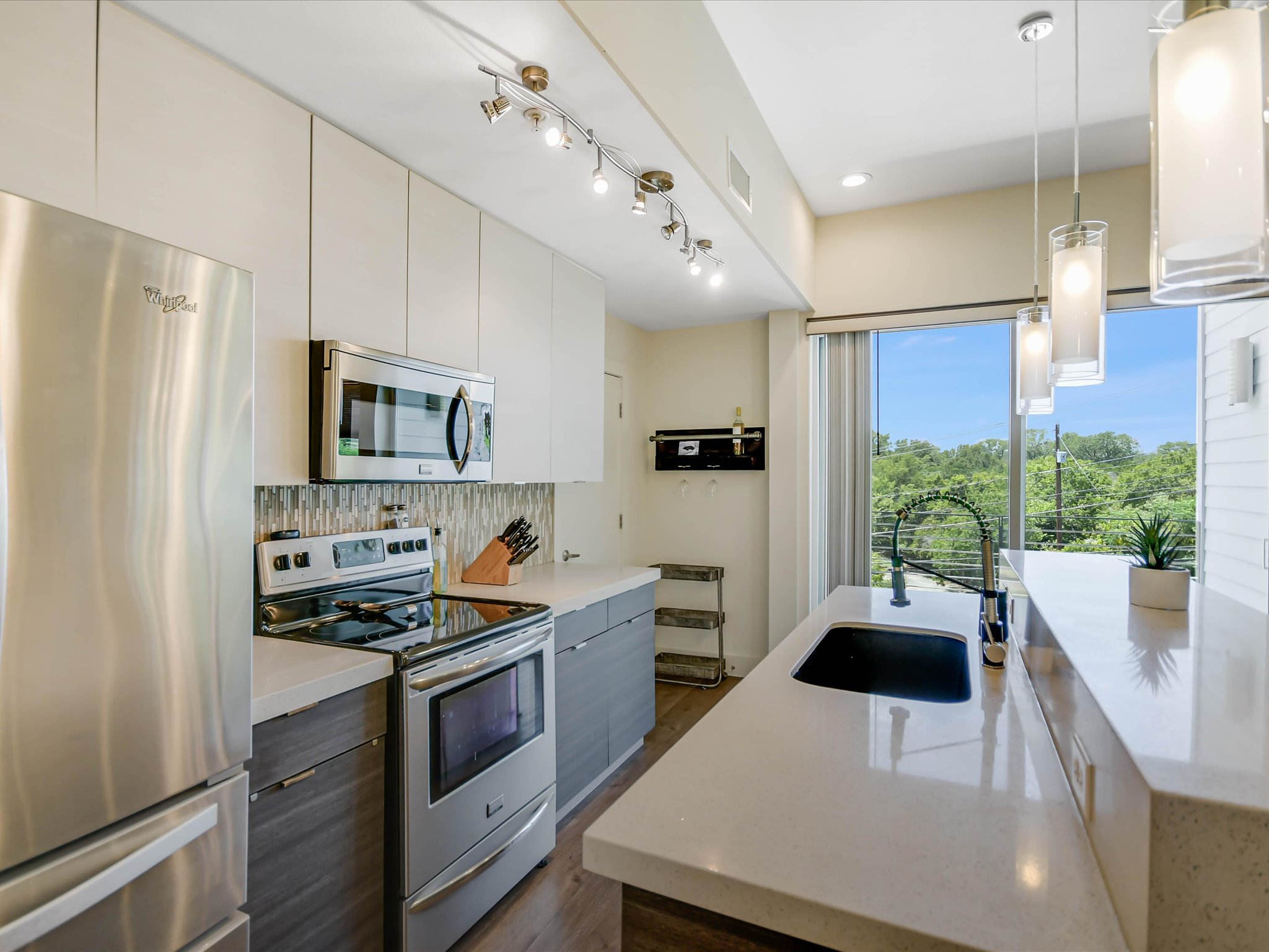 604 North Bluff Drive, Unit 101 Austin, TX 78745 - Photo 13 of 22 Kitchen featuring appliances with stainless steel finishes, modern cabinets, tasteful backsplash, dark wood-style flooring, and recessed lighting