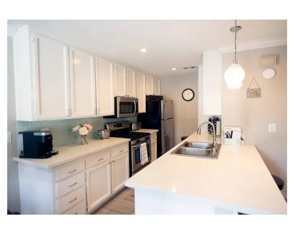 a kitchen with stainless steel appliances kitchen island granite countertop a sink and white cabinets