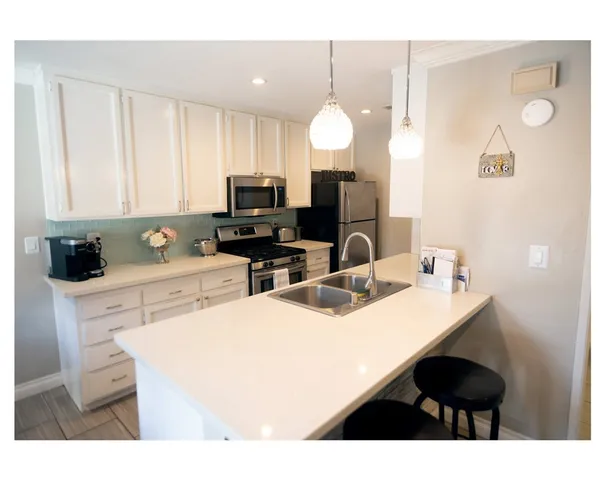 a kitchen with stainless steel appliances a sink a stove a refrigerator a center island and cabinets