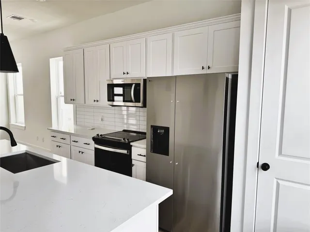 a kitchen with granite countertop white cabinets and stainless steel appliances