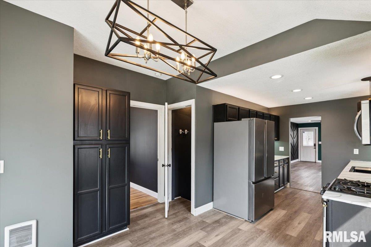 1911 23rd Street, Unit A Moline, IL 61265 - Photo 12 of 28 a view of a refrigerator in kitchen and an empty room with wooden floor