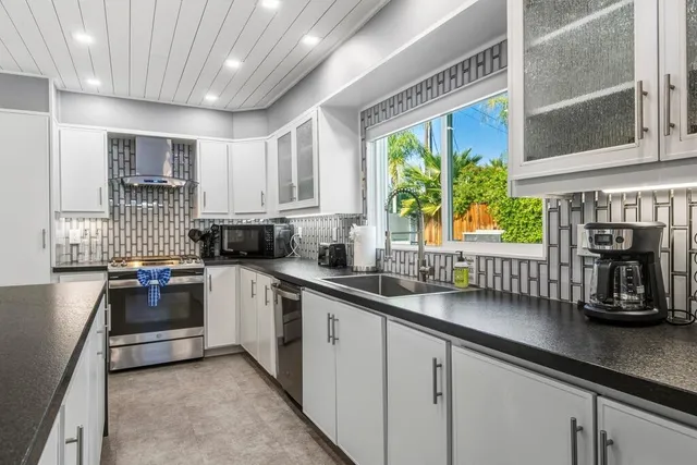 a kitchen with stainless steel appliances granite countertop a sink a stove and cabinets