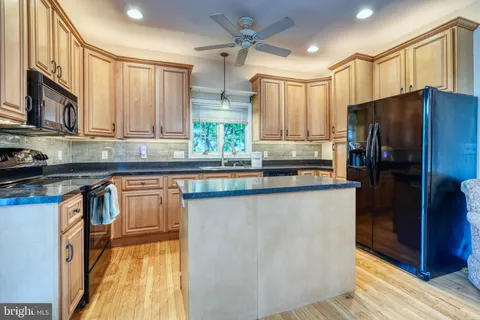 a kitchen with granite countertop a refrigerator a sink a stove and cabinets