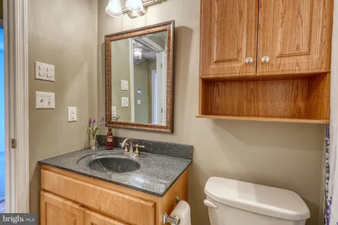 a bathroom with a granite countertop sink and a toilet