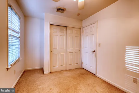 a view of a hallway with wooden floor and a bathroom