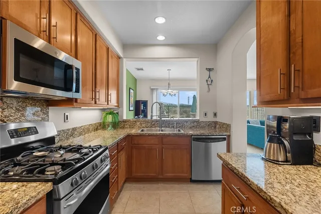 a kitchen with stainless steel appliances granite countertop a stove top oven a sink dishwasher and a microwave oven with large wooden cabinets